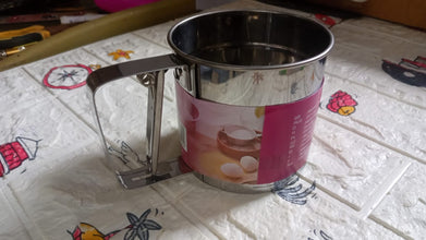 Easy-to-use manual flour sifter with a shaker mechanism, ideal for precise and lump-free baking.